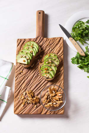 Sliced avocado on toast bread with nuts. Breakfast and healthy food concept. Top viewの写真素材