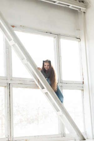 Young girl child climbing on high balk. Danger and hazard concept. Children home hazards. Staged photo.の写真素材