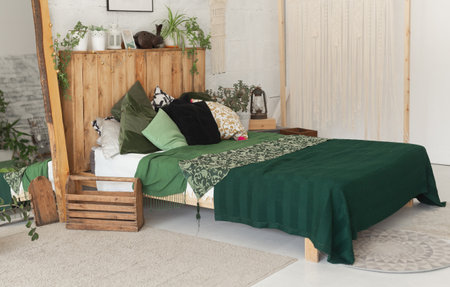 Comfortable bed with new green linens in eco style room interior