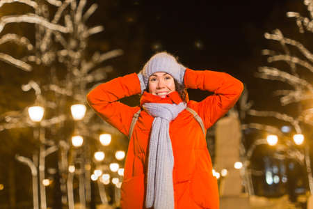 Winter holiday season. Christmas, New Year concept. Funny happy woman spend time having fun near illuminated and decorated showcase on city street.の写真素材