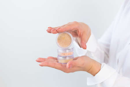Female hands holding face powder on a white background. Isolated background. Space for textの写真素材