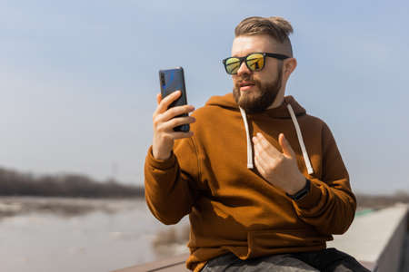 Social media communication. Man video call using mobile smart phone spring outdoorsの写真素材