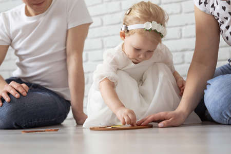 Baby child with hearing aids and cochlear implants plays with parents on floor. Deaf and rehabilitation conceptの写真素材