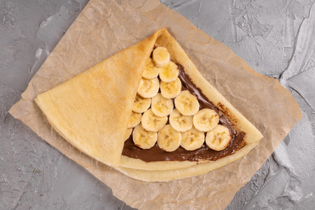 Crepes stuffed with chocolate spread and banana on white plate. Thin pancakes, blini. Sweet dessert. french cuisine top viewの写真素材