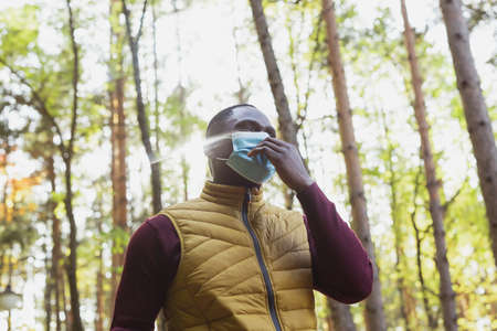 Handsome african american man wearing casual clothes and medical mask smiling happy walking in...