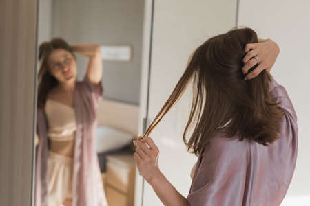 Happy morning. Attractive young woman looking in mirror at her apartmentの写真素材