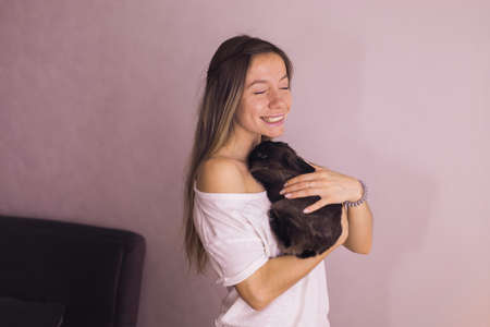 Young woman with adorable rabbit indoors, close up. Lovely pet and animal concept