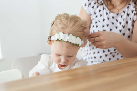 Mother helps to put on cochlear implant for her deaf little daughter. Hearing aid and deafness conceptの写真素材