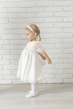 Baby child with hearing aids and cochlear implants on white brick wall. Deaf and health conceptの写真素材