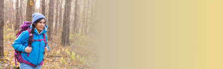 Banner hike and nature concept - Female tourist walking in autumn forest copy space
