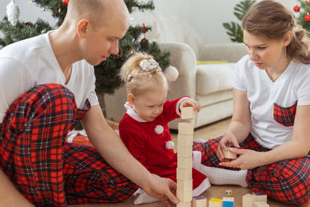Toddler child with cochlear implant plays with parents under christmas tree - deafness and innovating medical technologies for hearing aid and diversityの写真素材