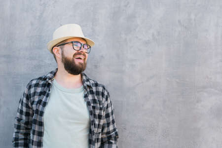 Handsome guy tourist looking happy wearing straw hat for travelling, standing against concrete wall...