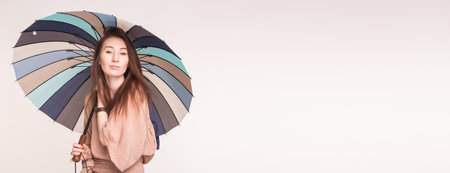 Pretty asian woman korean or japanese stands under umbrella on white background with copy space bannerの写真素材