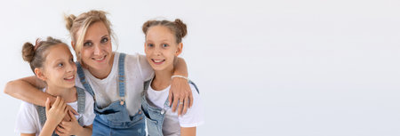 twins, family and children concept - portrait of a lovely mother embracing her twin daughters on white background banner with copy space and place for advertisingの写真素材