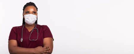 African american doctor in a medical mask over white banner background with copy space. Medicine, healthcare and people concept.の写真素材