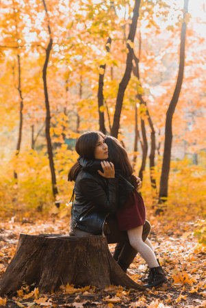 Mother and daughter spend time together in autumn yellow park. Season and single parent concept.