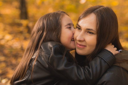 Mother and daughter spend time together in autumn yellow park. Season and single parent concept.