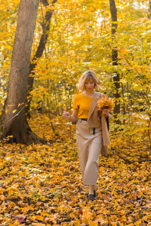 Walking woman on a fall day in the beautiful autumn park. Season and loneliness conceptの写真素材