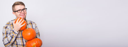 Banner harvesting, halloween and people concept - Man in black glasses holding three pumpkins over white background with copy spaceの写真素材