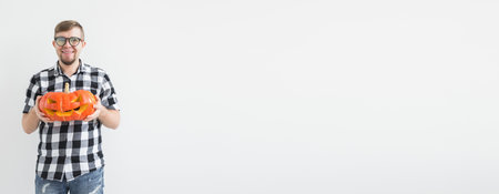 Banner happy funny man holding a jack o lantern carved halloween pumpkin in light room with copy spaceの写真素材