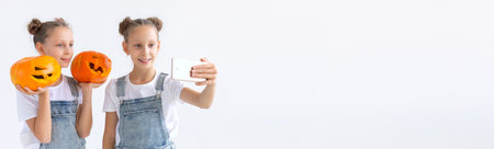 Banner happy Halloween, holidays and childhood concept - Cute little twins sisters girls with a pumpkins Jack-o-lantern having fun while spending time indoors copy spaceの写真素材