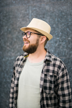 Handsome guy tourist looking happy wearing straw hat for travelling, standing against concrete wall background with copy spaceの写真素材