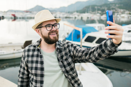 Traveller man taking selfie of luxury yachts marine during sunny day - travel and summer conceptの写真素材