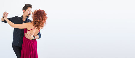 Banner social dance, bachata, kizomba, salsa, tango concept - Woman dressed in red dress and man in a black costume over white background with copy spaceの写真素材