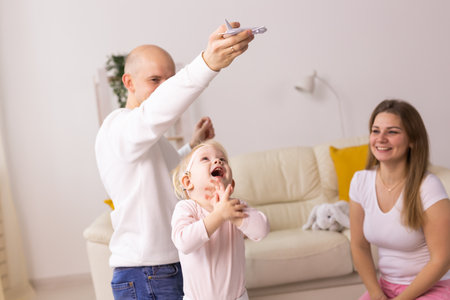 Happy child girl with cochlear implant having fun with her family - hearing aid for deaf and innovative health technology conceptの写真素材