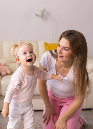 Cochlear implant on the child girl head and playing with mother Hearing aid and deafness and innovative health technology conceptの写真素材