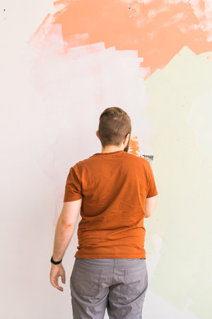 Young man using spatula and plastering of wall with white fresh finishing putty. Closeup. Repair work of home.の写真素材