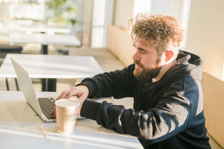 Close-up male guy portrait resting in coffee shop chatting in social networks skilled freelancer enjoying remote job typing publication for web blog on laptopの写真素材