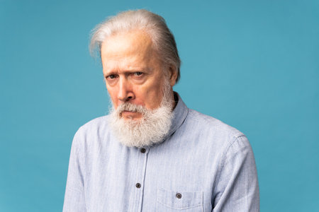 Portrait of unhappy grumpy pissed off senior mature man on blue background. Negative human emotions,...