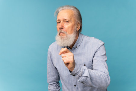 Portrait of unhappy grumpy pissed off senior mature man on blue background. Negative human emotions,...