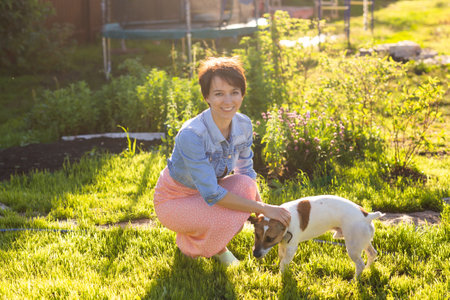 Young woman plays with her dog on the grass on backyard. The concept of animals and friendship or...