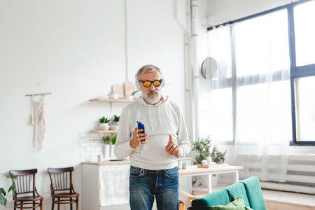 Senior man dance and using smartphone app for creating playlist music and - Elderly male having fun dancing with mobile phone technologyの写真素材