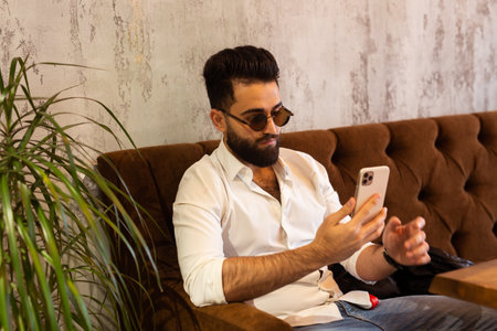 Entrepreneur uses phone mobile. Young handsome businessman arab muslim in business center. Technologies and business concept.の写真素材