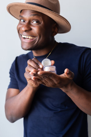 African american man holds mineral facial powder for perfect make-up for women - male make-up artist...