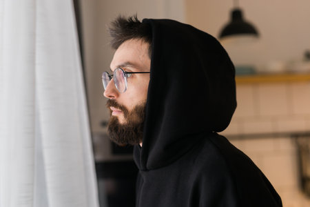 Side view of man longing and looking through window in sad day - depression and melancholy conceptの写真素材
