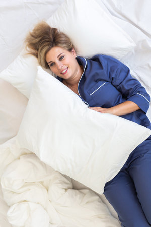 Cheerful woman lies in bed rest morning comfort - sleep time and relax