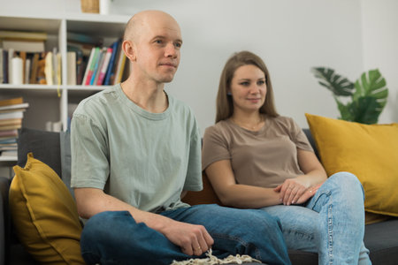 Young couple relaxing and watching TV at home, they focus on a dramatic moment in film - streaming service and free time conceptの写真素材