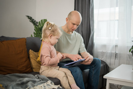 Deaf child girl with cochlear implant studying to hear sounds and have fun with father - recovery after cochlear Implant surgery and rehabilitation conceptの写真素材