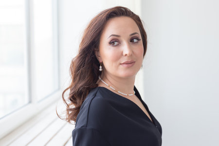 Young beautiful woman wearing elegant white pearl necklace, earrings posing indoors background. Beauty and fashion portrait. Jewellery and accessories conceptの写真素材