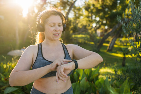 Young plus size woman with smart watch. Girl training in park. Woman with fitness tracker.の写真素材