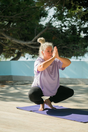 Senior woman with dreadlocks in stretching position by the sea at morning. Elderly woman doing yoga near beach.の写真素材