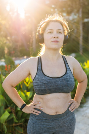 Fat woman and sports. Girl doing exercise for weight loss in the fresh air and smiling after training.の写真素材