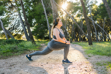 Adorable fat woman in tracksuit is engaged in fitness outdoor side view portrait copy space . Young...
