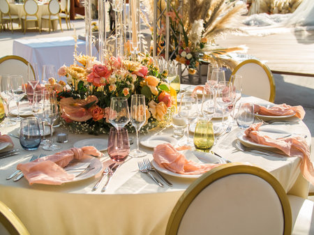 Wedding banquet concept. Chairs and round table for guests, served with cutler and, flowers and crockery and covered with a tableclothの写真素材