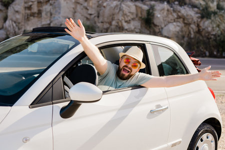 Happy man sitting in white convertible car with beautiful view and having fun - travel summer vacation and rental car conceptの写真素材