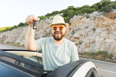 Handsome happy man showing key of new car - Rental and buy new car conceptの写真素材